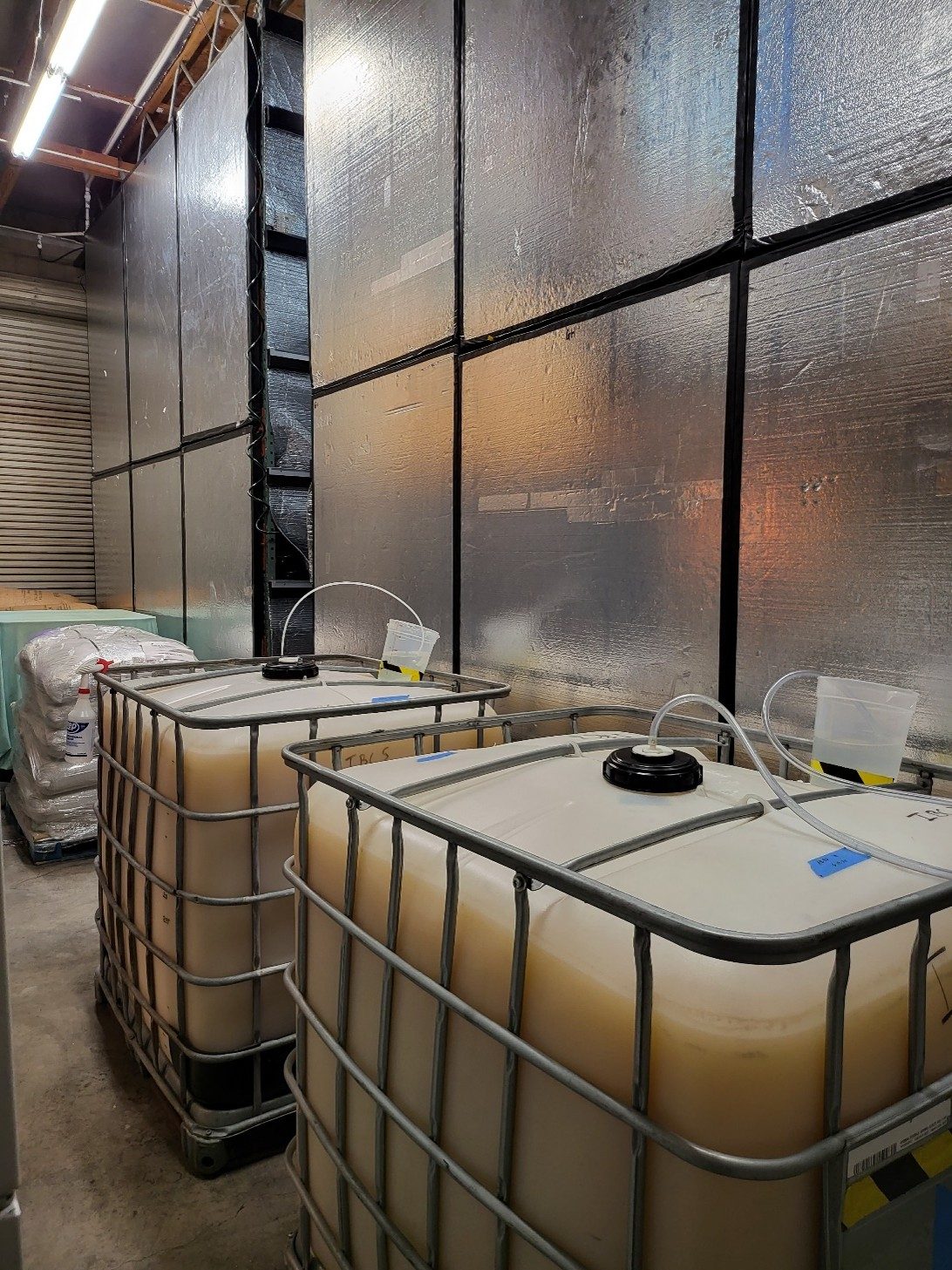 Foil-faced insulated panel walls inside a cold room, with IBC totes of kombucha staged against them